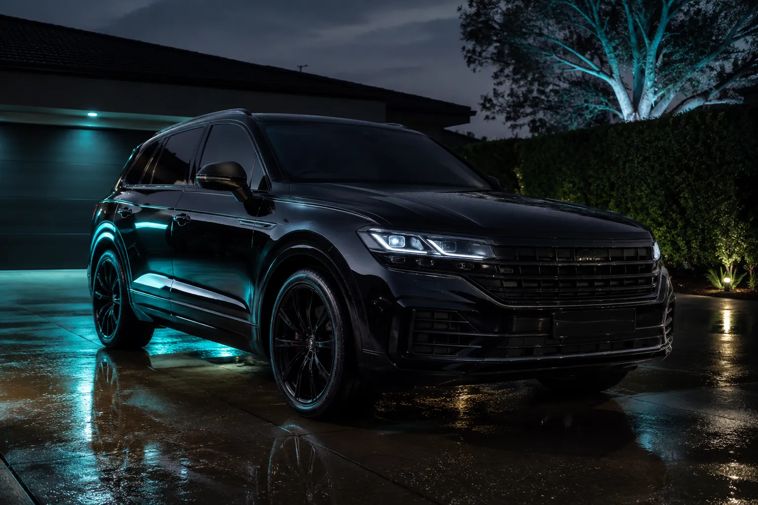 Freshly detailed black SUV on a wet driveway at dusk