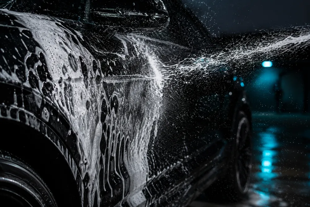 Snow foam rinsing off a black car panel